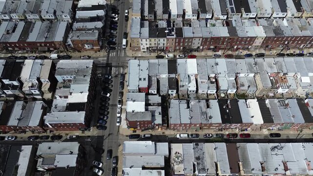 Parallel street rhythm along S Carlisle St and Mifflin St shows repeating rooflines, narrow corridors typical of South Philly. Light toned roofs, minimal foliage, even lighting settle Philly, PA