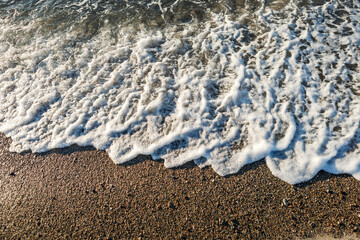 Abstract shoreline with white sea spray in upper third and dark wet sand dominating foreground, minimal coastal texture scene with natural contrast and moody seaside atmosphere © dreamcatcher