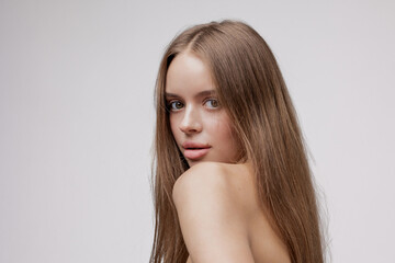 Naklejka premium Young woman with long hair poses against a plain background in a studio setting