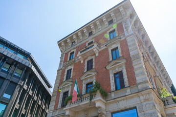Fototapeta premium Old house wall facade streets in center Milan city. Windows balcony with flag