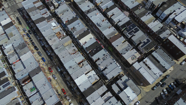 Tight residential roofing around S Hicks St and Wolf St reveals compact blocks narrow corridors and consistent South Philly geometry. Flat gray roofs, patched membranes, warm daylight, Philly, PA