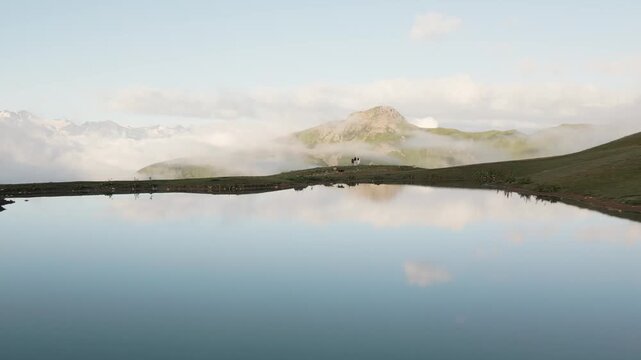Tourists with a dog standing by the mirror-like Koruldi Lakes in Georgia. A peaceful mountain landscape in Svaneti with reflections, hiking, and pet-friendly adventure in Georgia Alps