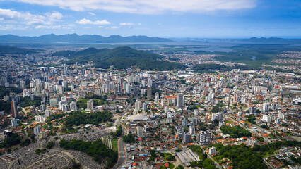 Fototapeta premium Aerial view of Joinville with dense urban area, green hills and Babitonga Bay in the background, Santa Catarina.