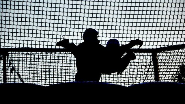 Athletic silhouette jumping high on a trampoline net, enjoying leisure and activity