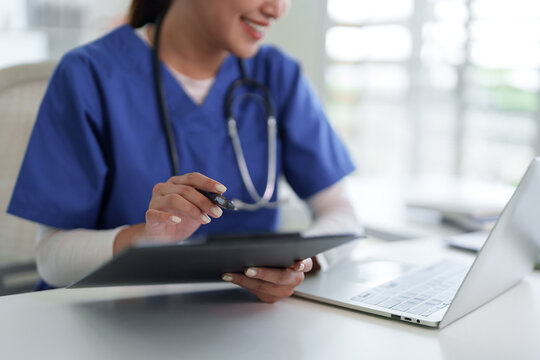 Asian medical professional adult woman works laptop computer clinic office diligent patient data documentation healthcare technology