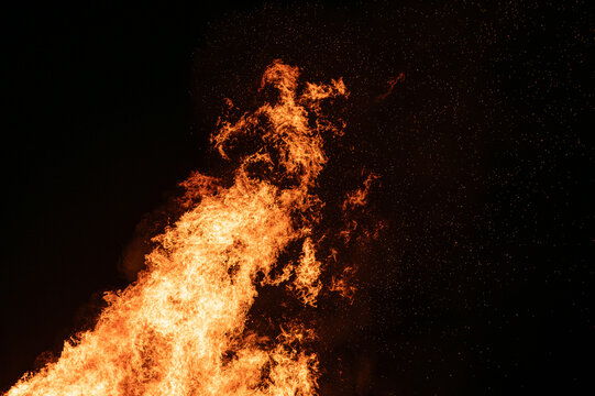 Lodernde Flammen mit Funkenflug bei Nacht vor schwarzem Hintergrund