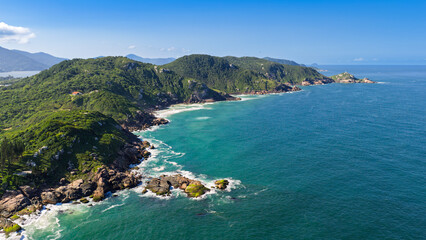 Aerial view of rocky headland with lush green hills and turquoise Atlantic Ocean, Florianopolis. © Marcio Eneas