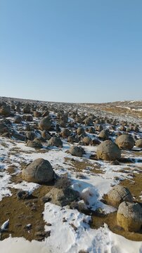 Grand winter aerial drone footage of snow-covered stone concretions in the Torysh Valley. These unique spherical boulders are the remains of the ancient Tethys Ocean floor. An incredible winter landsc