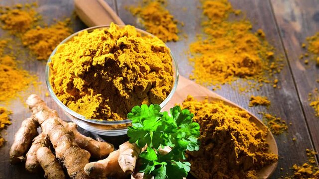A bowl of turmeric powder on wooden table.