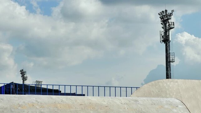 Young boy riding a kick scooter, jumping during a trick in a concrete skate park