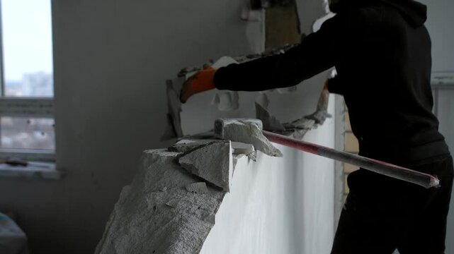 Worker breaks concrete and throws large broken slab aside with hands in slow motion.