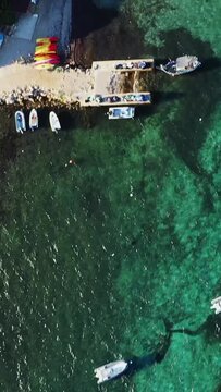 Drone shot of a parking lot surrounded by lush greenery near Plage du Petit Sperone in Corsica, France. Several cars are parked along a dirt road in a scenic natural setting.