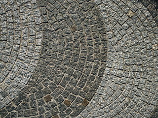 A close-up of gray granite pavers laid in a semicircular arc. A concept for a durable natural stone flooring solution.