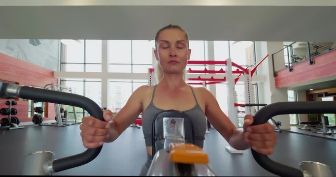 Woman Exercising on Rowing Machine in Modern Gym
