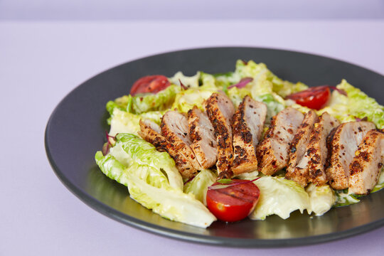 A perfectly grilled chicken breast served on a vibrant bed of fresh vegetables, including crisp lettuce, ripe tomatoes, colorful bell peppers, and tender asparagus. 