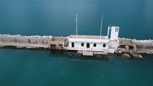 Aerial view of Greek island chapel on marina entrance breakwater