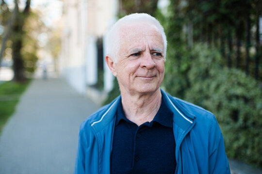 Smiling adult senior man 60-65 year old with gray hair outdoors. Close up portrait of mature person. Wellbeing lifestyle