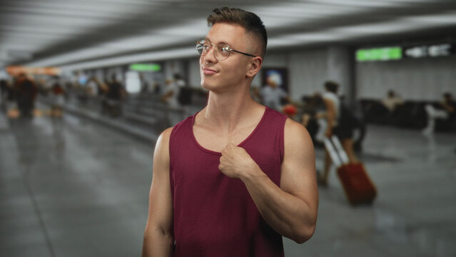 Man tugs shirt at chest and smirks in airport concourse amid moving travelers and luggage; confidence swagger.