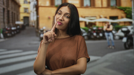 Obraz premium Woman brunette with finger to lips for silence in street crosswalk by scooters and building; silence.