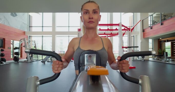 Woman Exercising on Rowing Machine at Modern Gym
