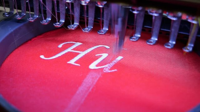 Machine embroidery on red fabric with white thread. Text embroidery. Close up 4k video