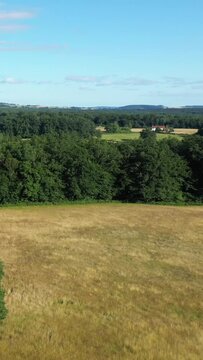 Wide view of a rural Morvan landscape with grassy fields, dense green forest, and clear blue sky on a sunny day.