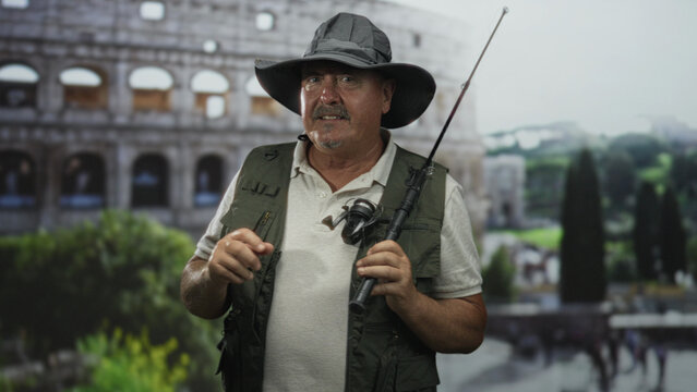 Man fisherman holding fishing rod and reel, wearing hat and vest, visible hands on pole in front of colosseum set in a studio; travel nostalgia.