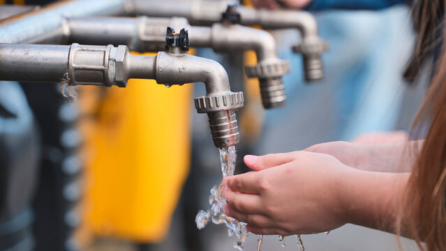 Child hands washing under flowing water from outdoor tap for hygiene and health