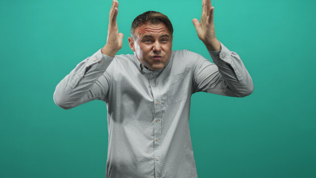 Man presses temples, puckers cheeks and gestures with raised hands in studio; frustration concentration.