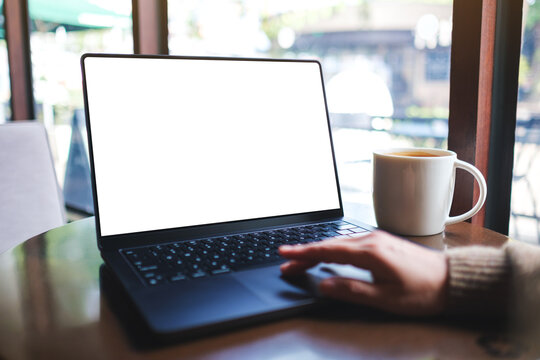 Mockup image of a woman working on laptop computer with blank white desktop screen while drinking coffee in cafe