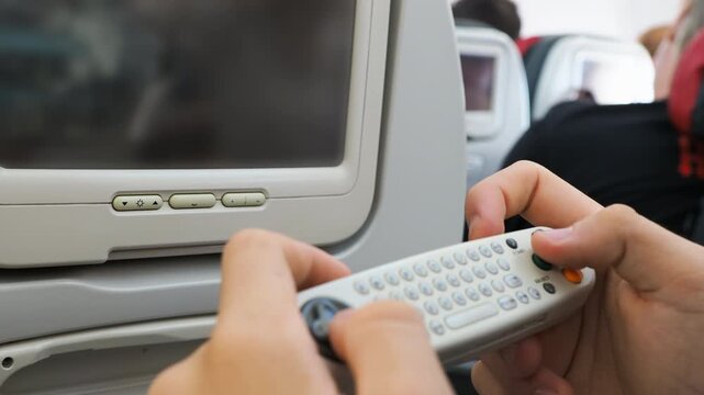 Hands holding wireless controller to navigate screen in commercial aircraft cabin