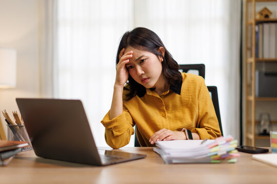 Stressed young Asian woman experiencing a headache and burnout