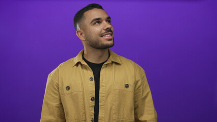 Obraz premium Man face looking up in purple studio setting wearing brown jacket with slight head tilt and casual pose; curiosity.