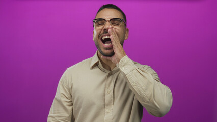 Obraz premium Man laughing with eyes closed showing teeth in purple studio setting wearing glasses and beige shirt; happiness confidence.