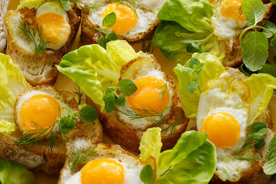 Sandwiches with fried quail eggs, lettuce and herbs, top view. Delicious breakfast.
