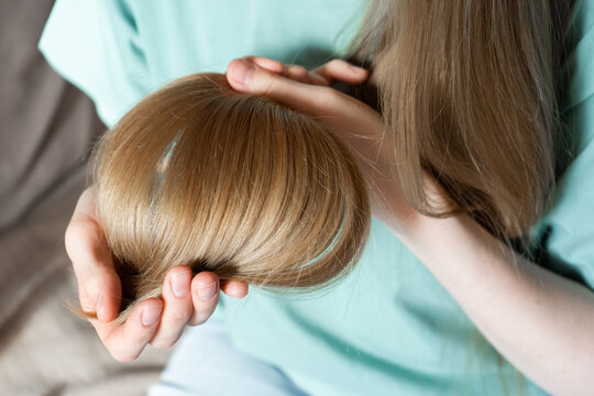 Woman holding hair gently while checking for split ends at home  