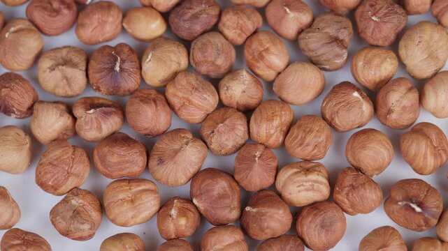 Hazelnut closeup display. Detailed macro shot of crunchy hazelnut kernels. Fashioned macro image capturing roasted hazelnuts with textured skin on pristine white surface