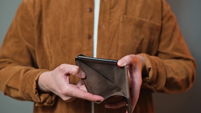 A man checks his wallet and shows the camera that it's empty. Poverty, bankrupt