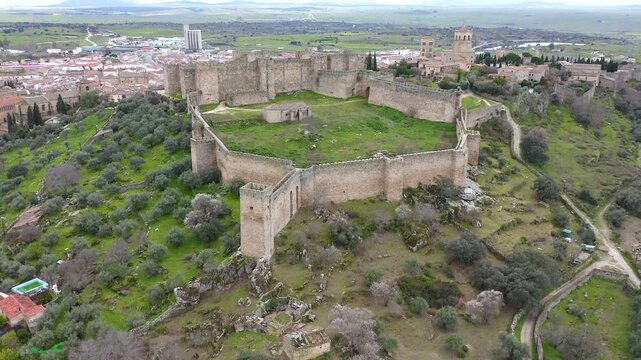 Aerial view of Trujillo Castle ruins in Caceres, Spain. Historic hilltop fortress remains open to visitors, medieval stone structures overlooking Castilla La Mancha landscape.