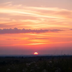 Obraz premium Vibrant orange sunset over landscape horizon.