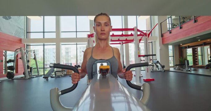 Woman Exercising on Rowing Machine in Modern Gym