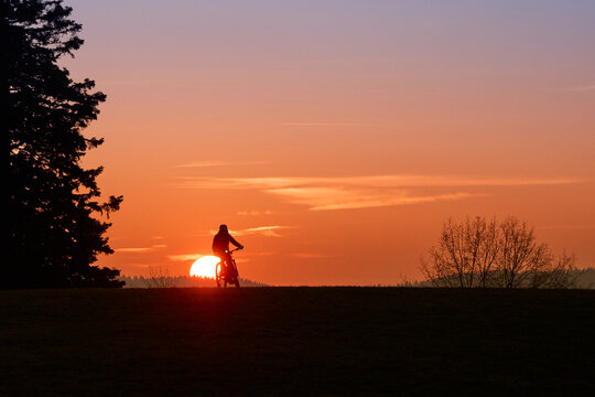 Woman with a mountain bike enjoying a scenic sunset in the Allg&auml;u region, Germany. Outdoor adventure, freedom, and active lifestyle in a peaceful alpine landscape with warm evening light.