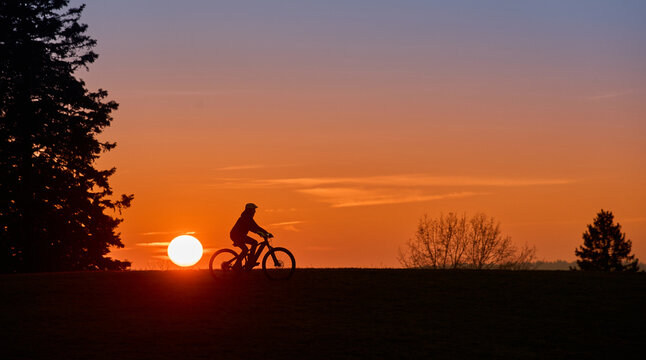 Woman with a mountain bike enjoying a scenic sunset in the Allg&auml;u region, Germany. Outdoor adventure, freedom, and active lifestyle in a peaceful alpine landscape with warm evening light.