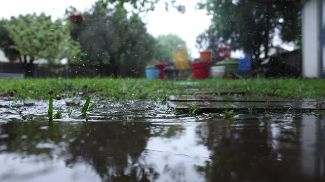4k video of residential backyard low angle ground surface of rain pooling and falling in puddle on overcast day in Texas.