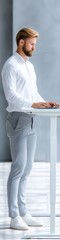 Obraz premium Young man stands at standing desk, typing