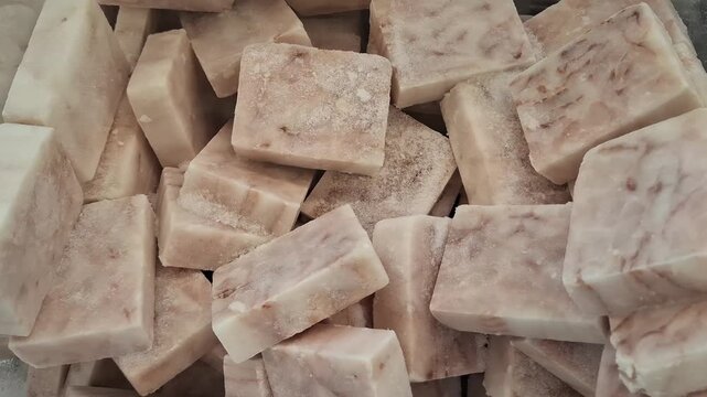 Frozen portioned fish fillet in heap. High-quality blocks of raw cod or pollock on retail freezer displays. White fish cubes for quick healthy meals, and gourmet seafood cooking preparations at home
