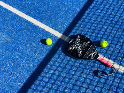 Faro, Portugal, February 18, 2026 Top view of a padel racket nox and a tennis ball placed on a blue court with white lines, symbolizing the sport and its equipment.