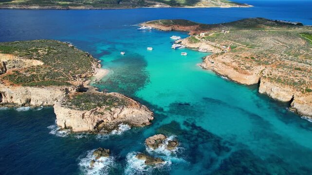 Aerial view of mesmerizing turquoise crystal clear blue water at Blue Lagoon with surrounding cliffs and caves and lush greens on Comino Island Malta on a warm sunny day in summer