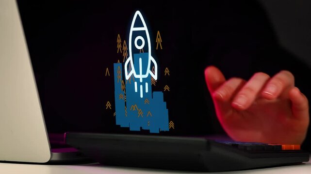 Manworking on a laptop with a digital rocket graphic and trees at night in a dimly lit room.