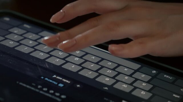 Hands typing on tablet keyboard in low light